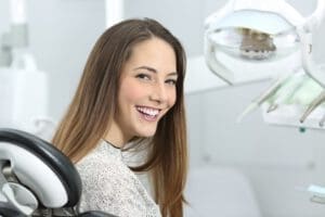 A woman sits in the dental chair and smiles