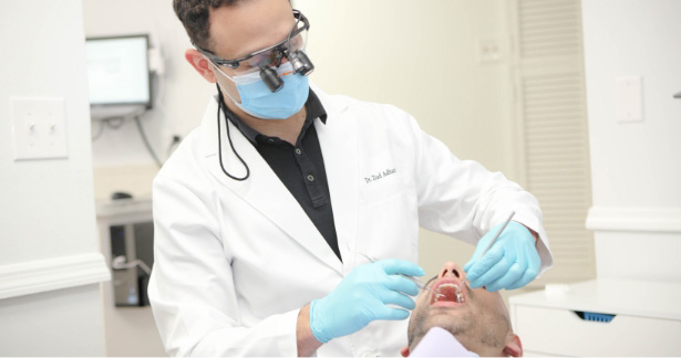Male patient opening his mouth while the dentist examines it
