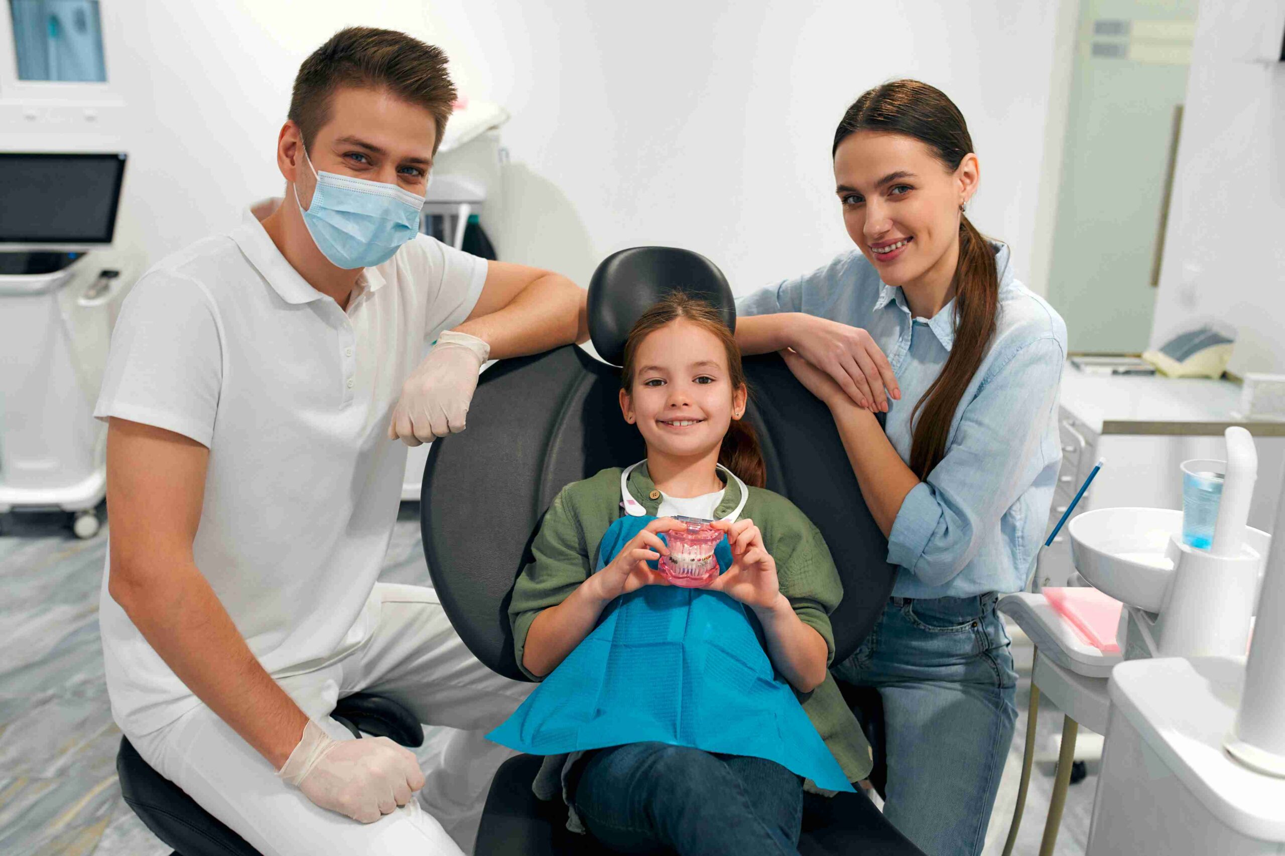 Child smiling with parents during a family dental visit.